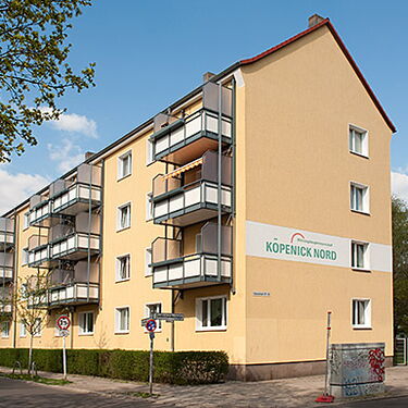 Ein mehrstöckiges Wohngebäude mit Balkonen und einem Schild "Köpenick Nord" steht an einer ruhigen Straßenecke.