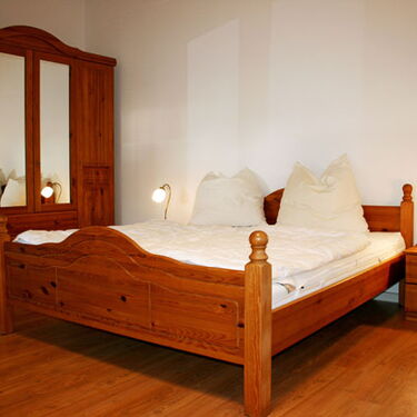 Gemütliches Schlafzimmer mit einem Holzbett und passendem Kleiderschrank im rustikalen Stil.