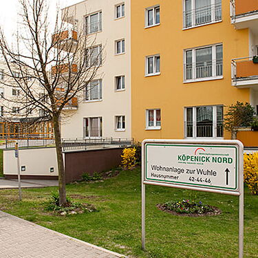Ein modernes Wohngebäude in Köpenick Nord mit einem Schild zur Wohnanlage zur Wuhle, umgeben von gepflegtem Grün.