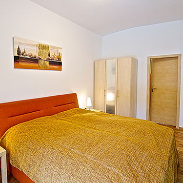 Ein gemütliches Schlafzimmer mit einem großen Bett, Holzschrank und einem Gemälde an der Wand im Waschhaus-Stil.