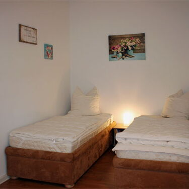 Zwei Einzelbetten stehen in einer gemütlichen Schlafnische mit sanfter Beleuchtung und dekorativen Wandbildern.