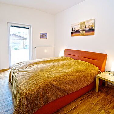 Gemütliches Schlafzimmer mit orangem Bett und Nachttischlampe, ideal für entspannte Nächte im Waschhaus.