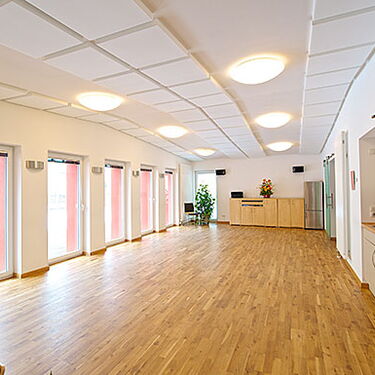Ein heller Festsaal mit Holzboden und mehreren Fenstern bietet Platz für Veranstaltungen im stilvollen Waschhaus.